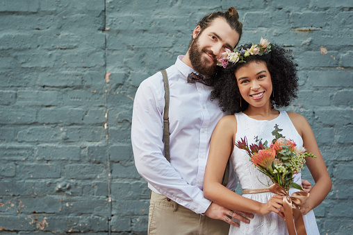 Shot of a newly married young couple celebrating their wedding day against a grey wall