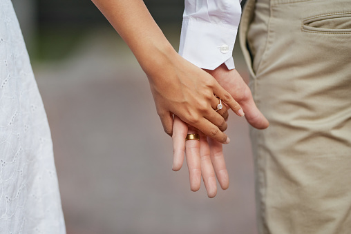 Cropped shot of a newly married young couple holding hands on their wedding day