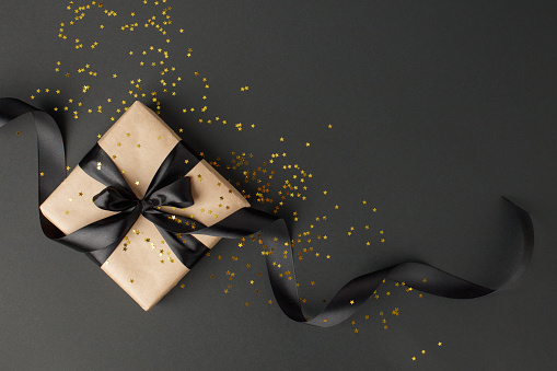 Caja de regalo o presente y confeti de estrellas de oro en la vista superior de la mesa negro. Plano lacomposición para cumpleaños, día de la madre, venta de viernes negro, Navidad, Navidad, nuevo yaer o boda. photo