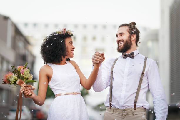 Here’s to a life full of smiles Shot of a newly married young couple celebrating their wedding day against an urban background eloping stock pictures, royalty-free photos & images