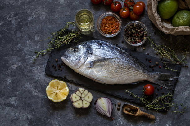 istock Dorado fish with greens and fresh vegetables on a dark background 1181238564