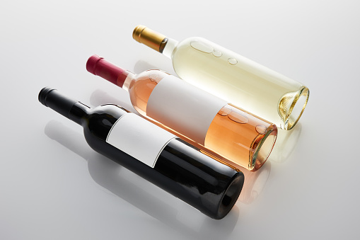 bottles with white, rose and red wine on white background