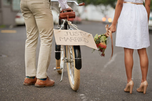 Guess who got hitched! Cropped shot of a newly married young couple walking through the city with a bicycle eloping stock pictures, royalty-free photos & images