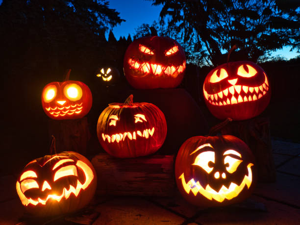 group of candle lit Halloween Pumpkin group of candle lit Halloween Pumpkin with blue sky in background halloween lantern stock pictures, royalty-free photos & images