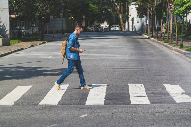 joven caminando en un paso de peatones por la calle de sao paulo - one cross fotografías e imágenes de stock