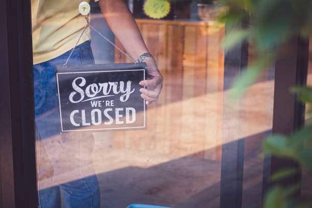 Woman Holding up a shop sign saying: Sorry we're Closed stock photo