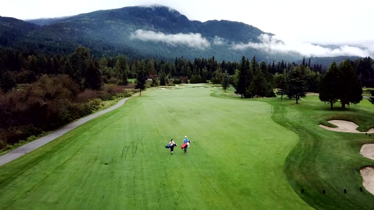 Male and female golfers walking down the fairway. Aerial footage of golfers. Couple bonding with sport.