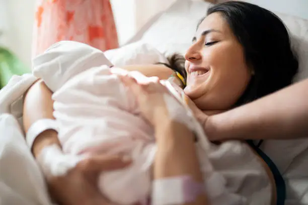 Photo of Mother breastfeeding newborn baby in hospital ward, first breastfeeding