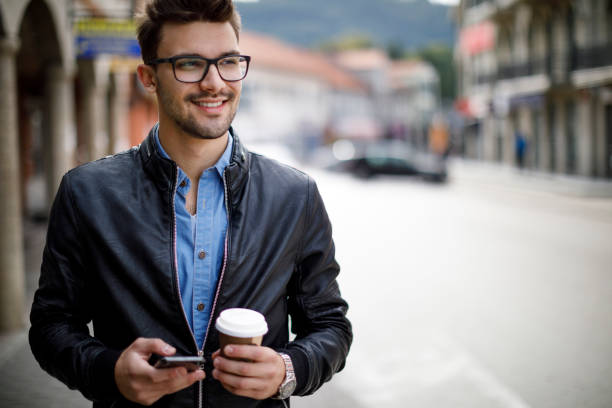 homem novo de sorriso que penduting para trabalhar - young adult lifestyles city life drinking - fotografias e filmes do acervo