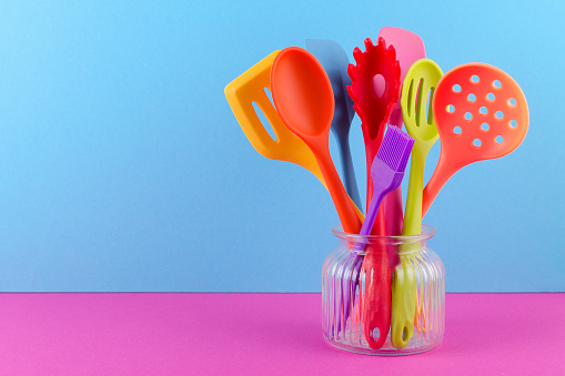 multi colored kitchen utensils on blue background and copy space