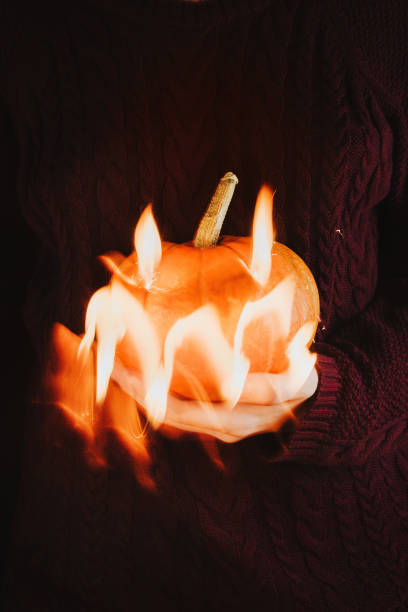 istock Woman's holding a pumpkin in her hand with a spooky face made with light, selective focus 1181258693