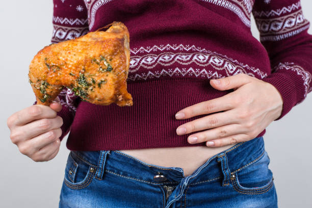 Junk food eating too much concept. Cropped close up photo of girl holding hands palm on big full abdomen feeling heartburn after fatty greasy nutrition isolated grey background Junk food eating too much concept. Cropped close up photo of girl holding hands palm on big full abdomen feeling heartburn after fatty greasy nutrition isolated grey background buttoning stock pictures, royalty-free photos & images