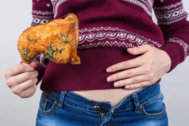 Photo of Junk food eating too much concept. Cropped close up photo of girl holding hands palm on big full abdomen feeling heartburn after fatty greasy nutrition isolated grey background