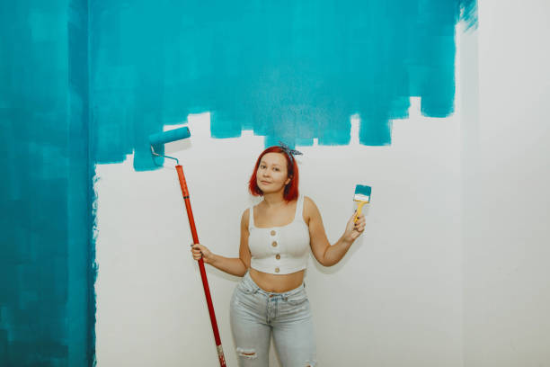 istock Girl paints a wall in blue. 1181260864