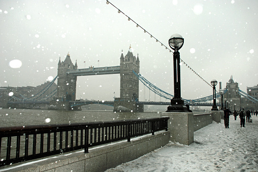 Snow falling from an overcast sky over a festive Christmas scene of tourist attractions in London, UK