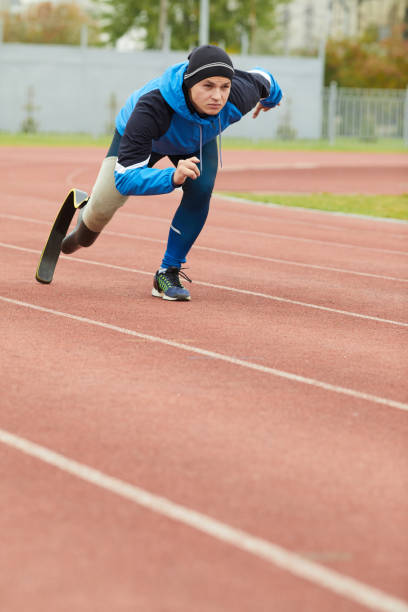 istock Serious young disabled sprinter with running blade running over outdoor stadium while participating in competition 1181262654