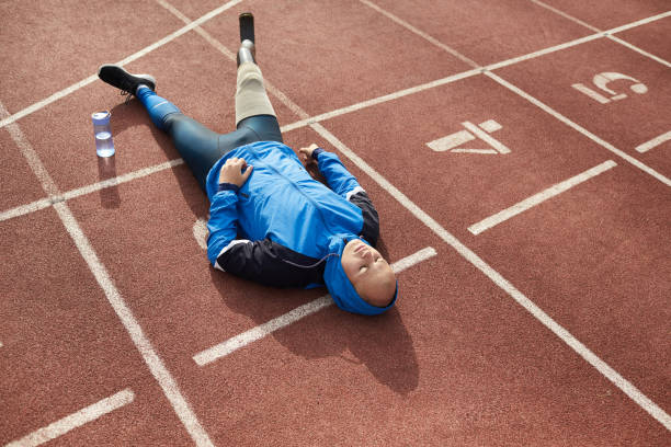 istock Exhausted young amputee guy in hoodie lying with closed eyes on stadium ground while resting after active training 1181262855