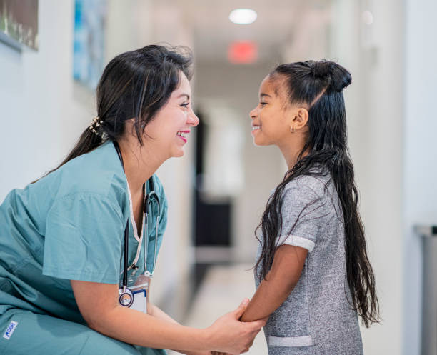 Doctor Talking to a Little Girl stock photo Female doctor bent down talking to her little patient oncology photos stock pictures, royalty-free photos & images