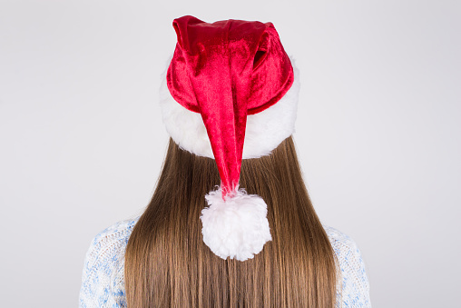 Back rear behind close up photo portrait of charming gorgeous lady having nice straight smooth silky hair wearing santa's hat on head isolated grey background