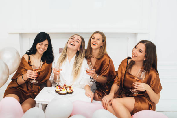 Pajamas party time. Beautiful charming girlfriends celebrating hen party, drinking alcohol and laughing at hotel Pajamas party time. Beautiful charming girlfriends celebrating hen party, drinking alcohol and laughing at hotel bachelor and bachelorette parties stock pictures, royalty-free photos & images
