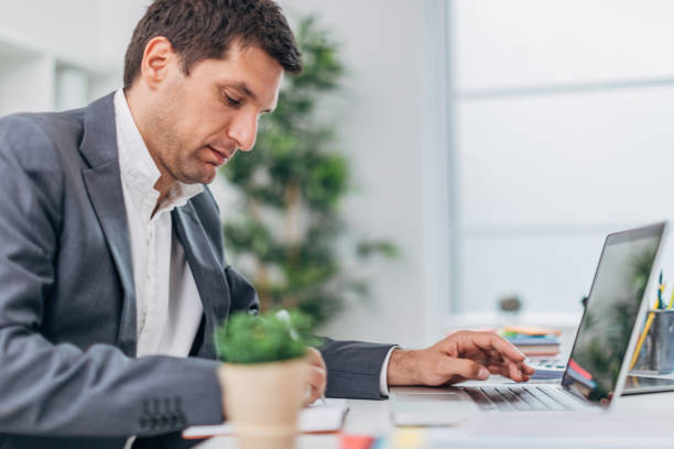 istock Businessman working on laptop and writing in notepad 1181266154
