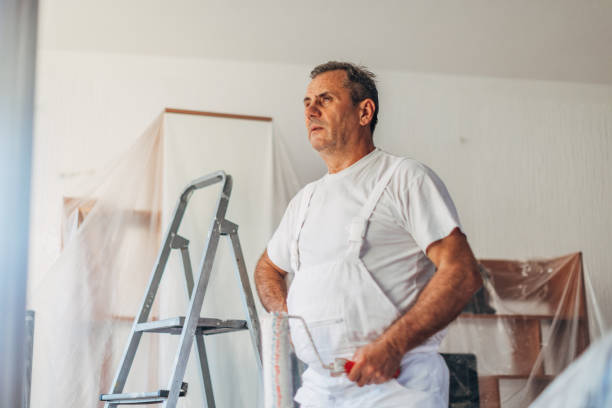 istock Senior painter holding paint roller and standing in living room 1181266749