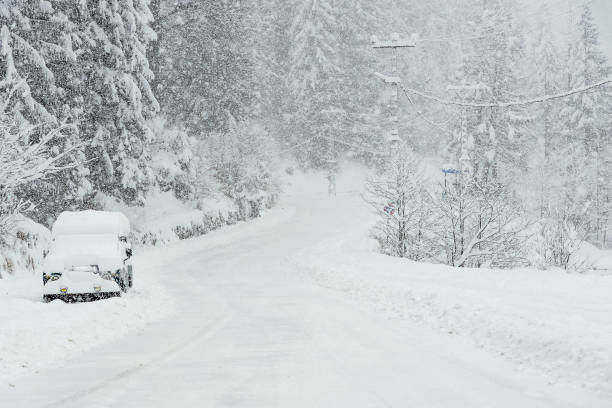 istock Snowy road in winter with an SUV parked. 1181266861