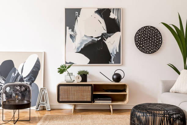 istock Stylish scandinavian living room interior with gray sofa, black lamp, design commode, tropical plants, decoration books and personal accessories. Mock up abstract paintings on the wall. Template. 1181271279