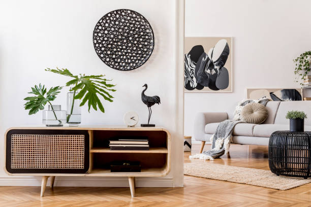 istock Scandinavian and design home interior of open space with wooden commode, gray sofa, design black rattan decoration, tropical leafs and elegant personal accessories. Stylish art home decor. Template. 1181271854