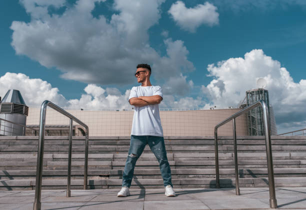 istock sports guy stands pose break dance dancer, hip-hop summer city background steps clouds. Active youth lifestyle, young male fitness movement workout breakdancer. In t-shirt jeans sneakers, sunglasses. 1181272573