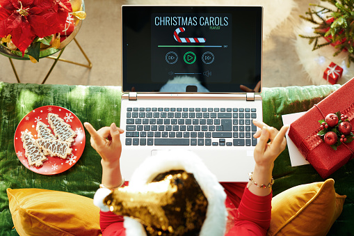 alegre mujer de moda escuchando música de Navidad en el ordenador portátil photo