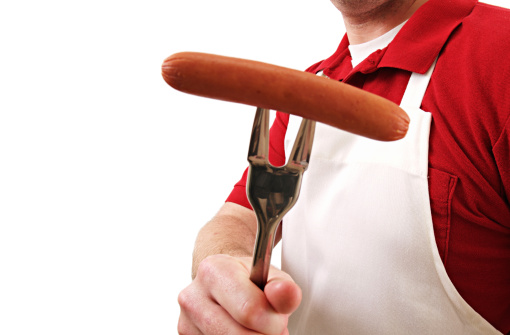 a man holding a hot dog at a cookout isolated on white.