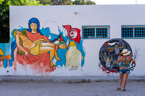 Tunisia. (Southern Tunisia). Island of Djerba. Erriadh. 07/02/2019. A woman looking to the draw made by the artist during the festival of Street Art Djerbahood.