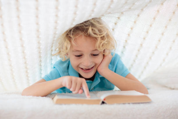 istock Child reading book in bed. Kids read books. 1181284287