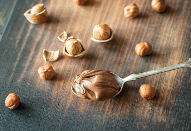 Spoon of chocolate paste with hazelnuts Spoon of chocolate paste with hazelnuts on the wooden background Teaspoon of Nutella stock pictures, royalty-free photos & images