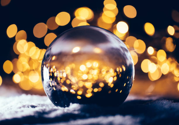 Christmas glass ball on snow. Lights shining through. Elegant greeting card
