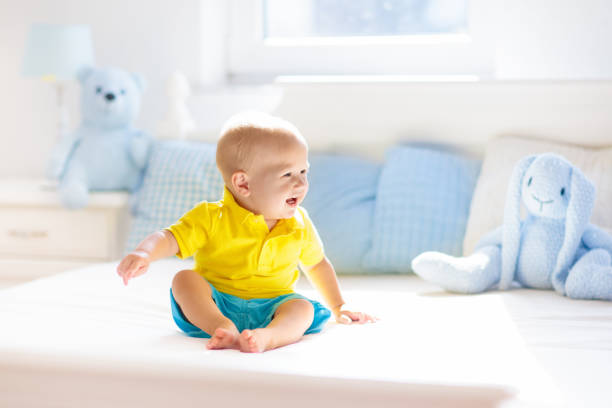 istock Baby boy playing on bed in sunny nursery 1181286333