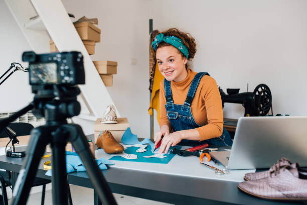 Young woman making vlog about making shoes Young woman filming the video blog about making leather shoes in her workshop. film studio photos stock pictures, royalty-free photos & images