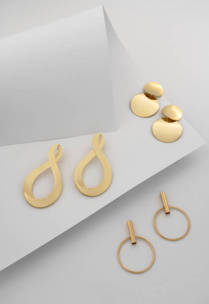 istock Three Golden earrings pairs on folded white paper background 1181305066