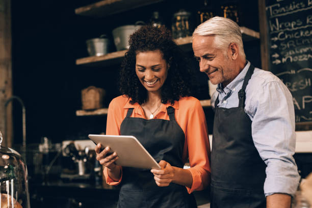 istock Smiling mature couple using a tablet in their cafe 1181305312