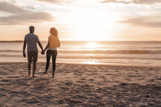 istock Laughing mature couple walking together on a beach at sunset 1181309999