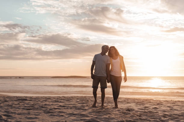 istock Smiling mature couple walking on a beach during sunset 1181311985