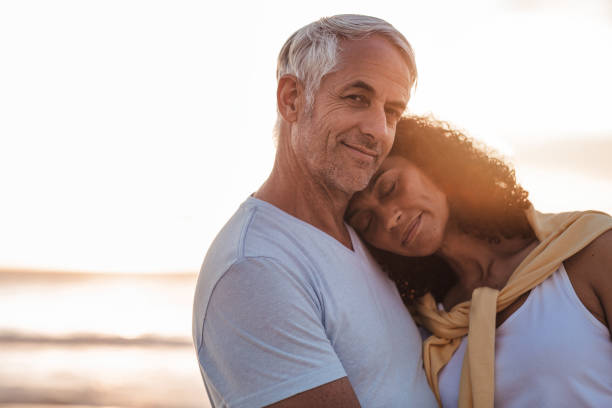 istock Smiling mature couple hugging on a beach at dusk 1181314199