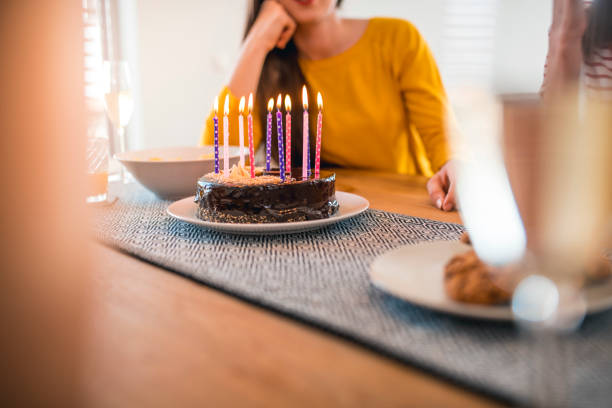 istock Young women with birthday cake at dining table 1181315292