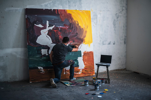 Modern artist painting emotionally in his studio.