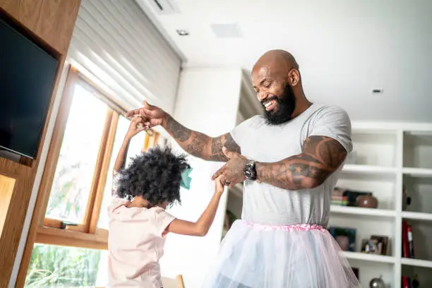 Funny father with tutu skirts dancing like ballerinas