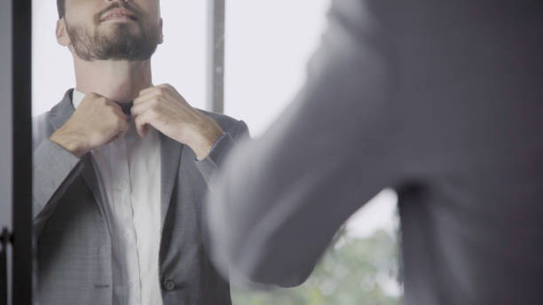 Man in formal suit getting dressed in dressing room for work or wedding.
