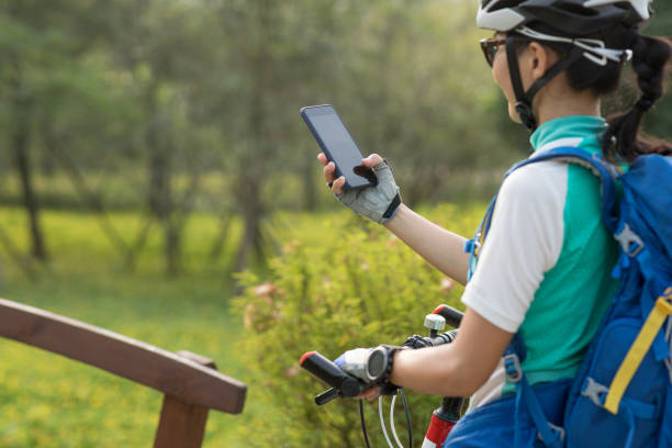 istock Woman using smartphone while riding bike on sunny day in park 1181336214