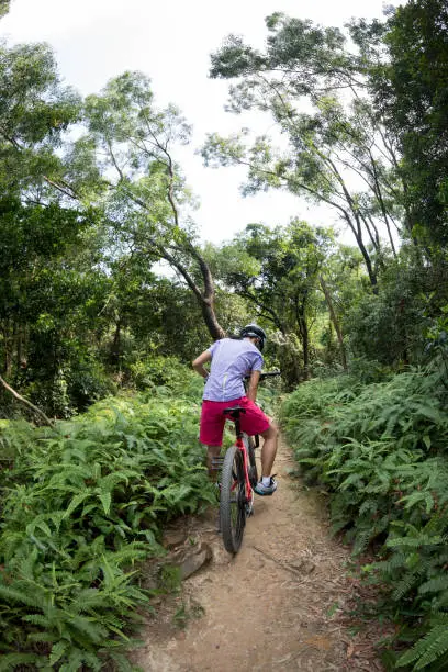 Photo of Cross country biking cyclist relax and drinking water on tropical rainforest trail