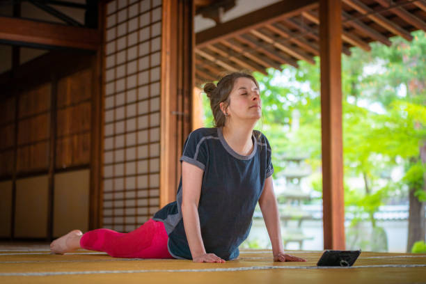 les femmes caucasiennes apprécient le yoga utilisant un smartphone dans un temple - zen like women temple meditating photos et images de collection